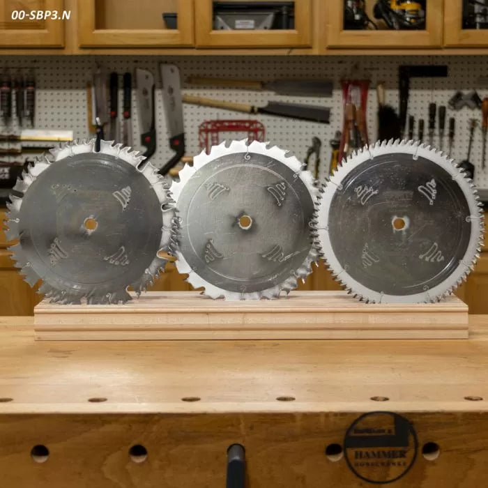 Three circular saw blades for woodworking displayed on a workbench in a workshop