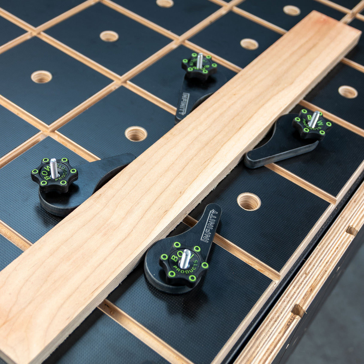 Eccentric cam clamps securing wood board on woodworking workbench with grid pattern