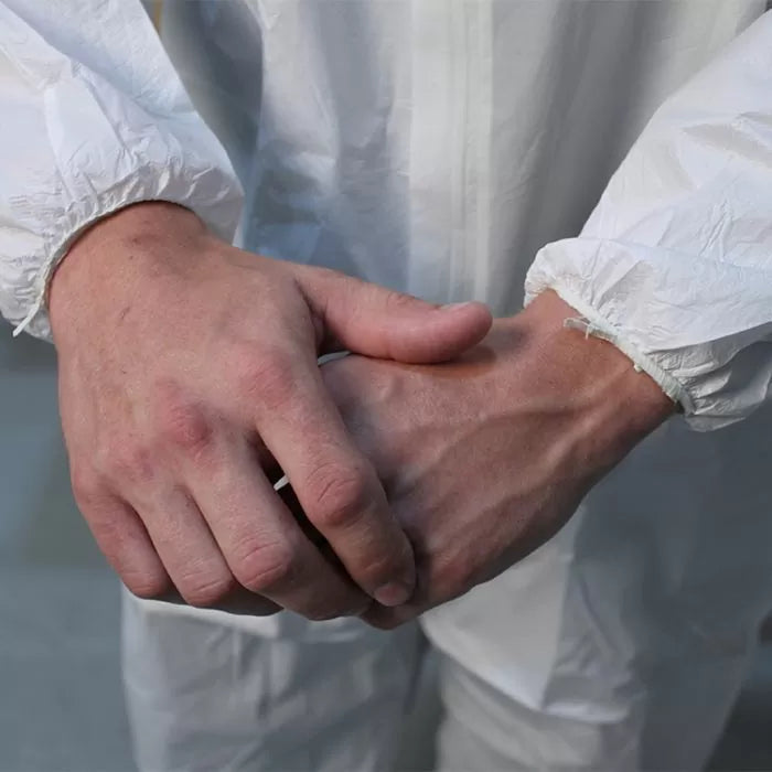 Close-up of hands in white protective coveralls for woodworking safety