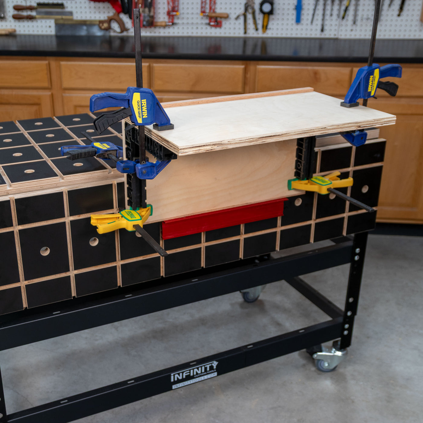 Woodworking bench with plywood clamped for assembly using quick-release clamps