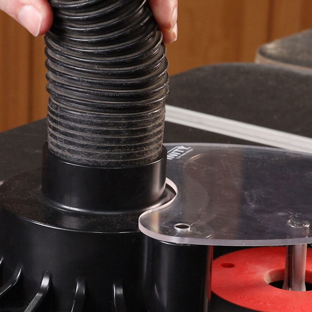 Close-up of a person adjusting a black flexible hose on a machine with a wooden background.