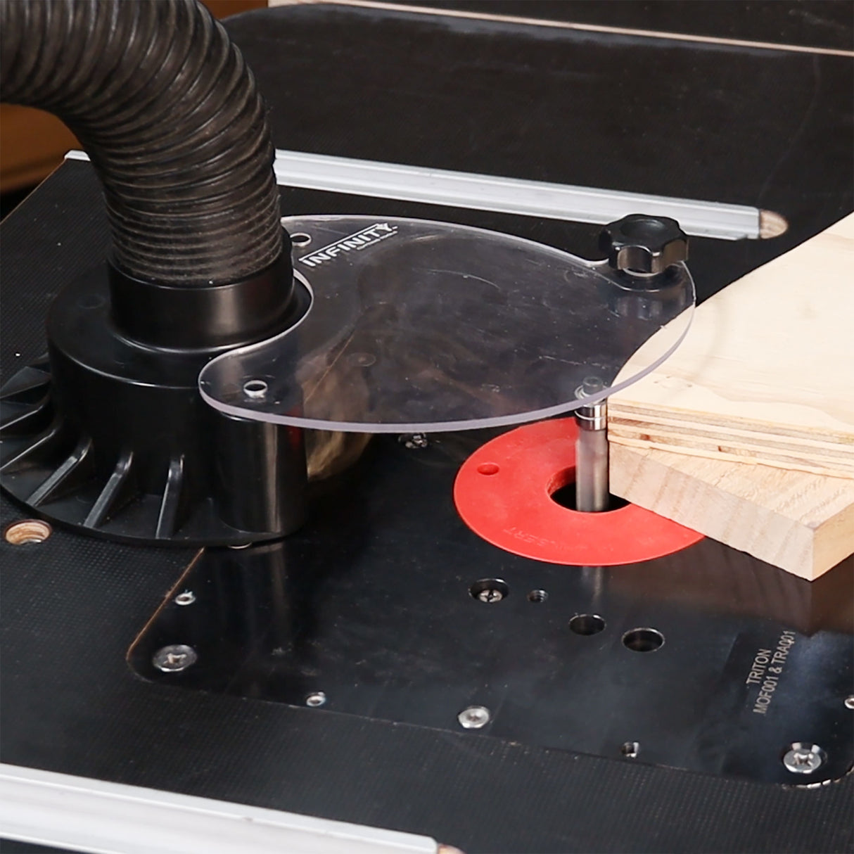 Router table with a router bit and wood piece on a workshop table.