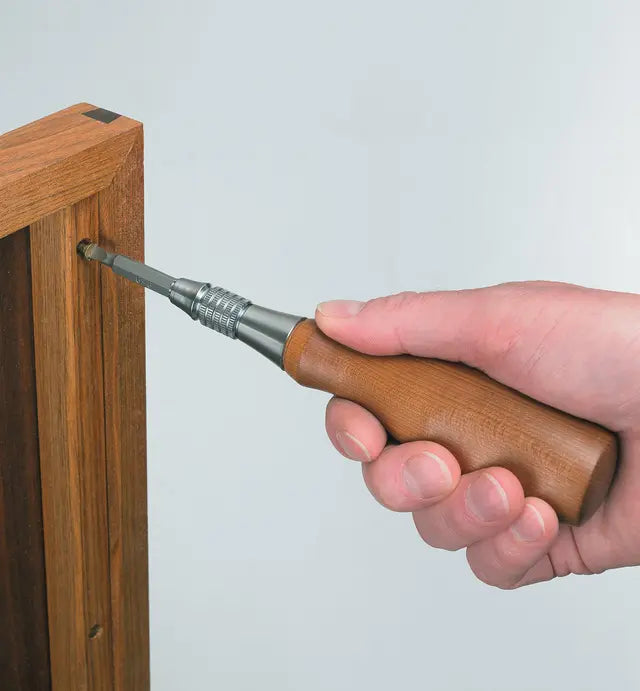 Hand using a woodworking screwdriver with wooden handle on cabinet joinery