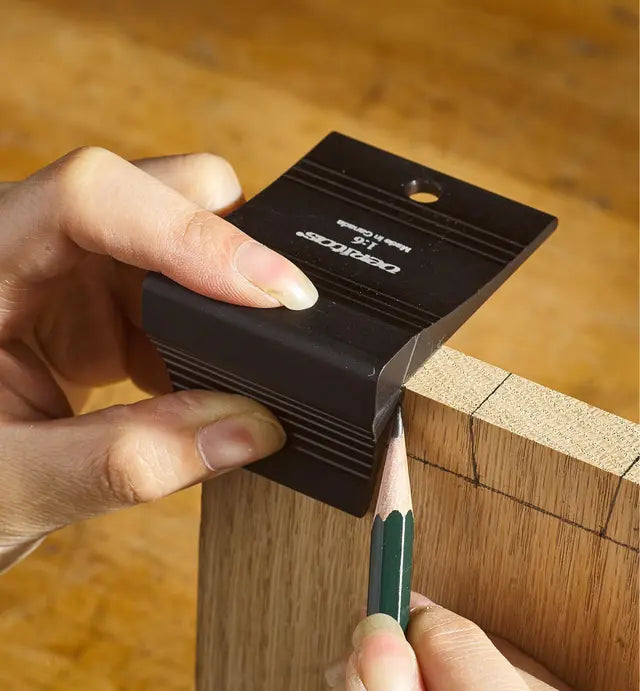 Hand using a woodworking marking gauge and pencil to mark lines on a wooden board
