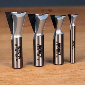 Set of four dovetail router bits on wood surface, ideal for woodworking precision cuts