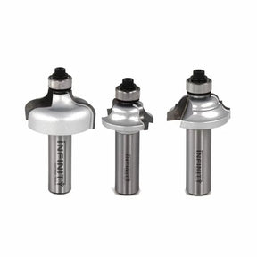 Three metal router bits for woodworking with ball bearing guides on a white background.