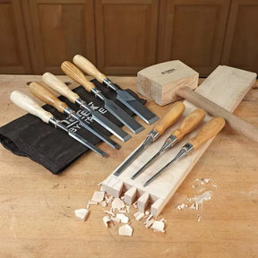 Woodworking chisel set, mallet, and woodblock on a workbench for precise wood carving.