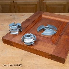 Ogee shaper cutter set displayed on a wooden cabinet door panel, woodworking tools