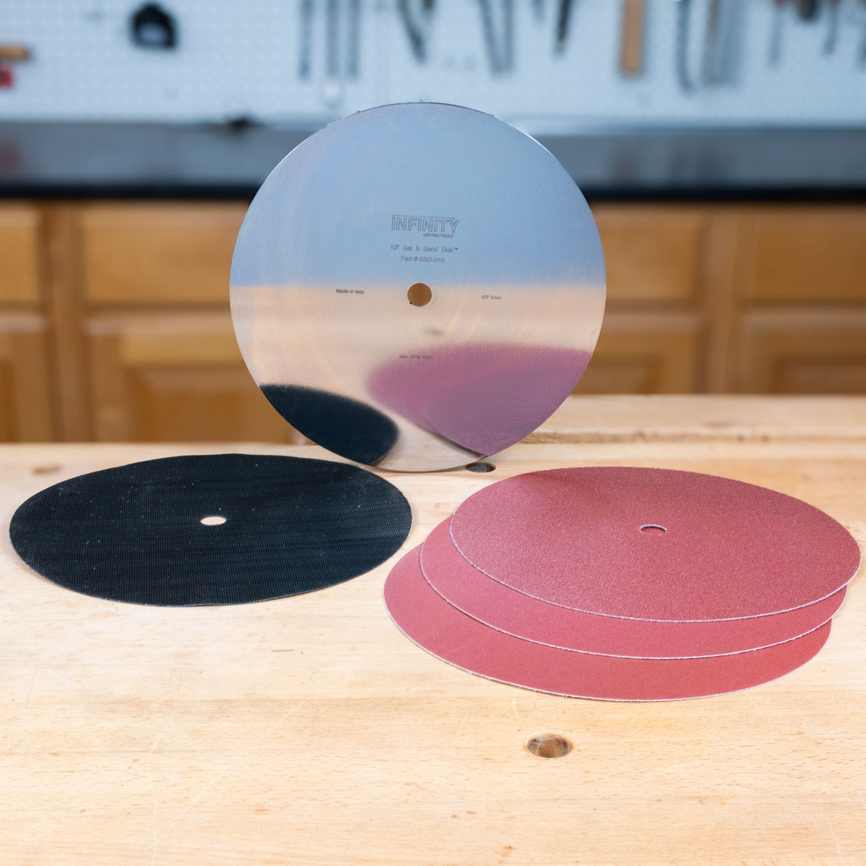 Metal sanding disc plate, hook and loop attachment and 3 sanding discs on a shop bench.