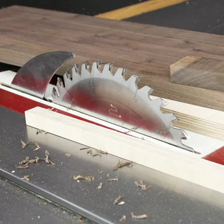 Table saw blade cutting wood, woodworking tool, dust and safety guard visible