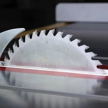 Close-up of circular table saw blade for woodworking, mounted in a saw table.