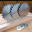 Three circular saw blades on a wooden surface with shims below.