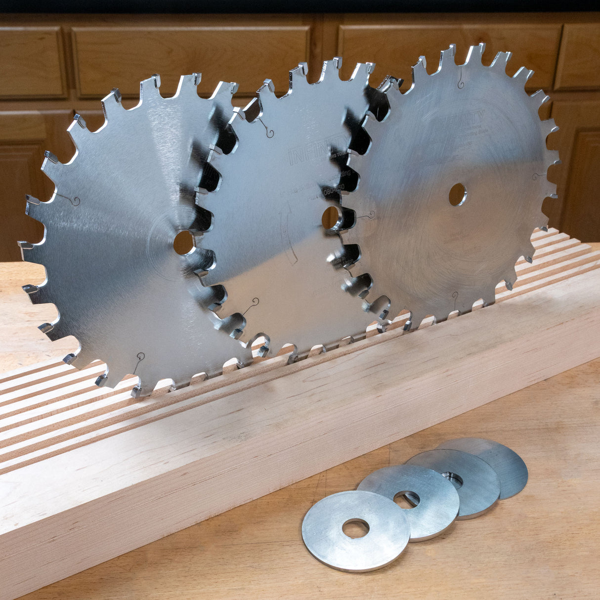 Three circular saw blades on a wooden surface with shims below.