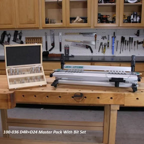 Dovetail jig and router bit set on workbench in woodworking shop with tools in background.