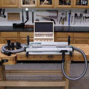 Dovetail jig with dust collection hose and router bit set on a woodworking bench in workshop