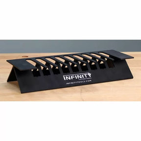 Black woodworking featherboard jig for saws, displayed on a wooden workbench.