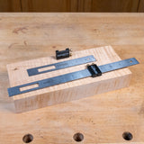 Two metal rulers on a wooden block with 'INFINITY' branding on a wooden surface.