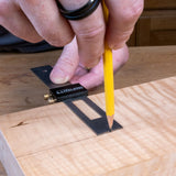 Person using a try square and pencil on a wooden surface