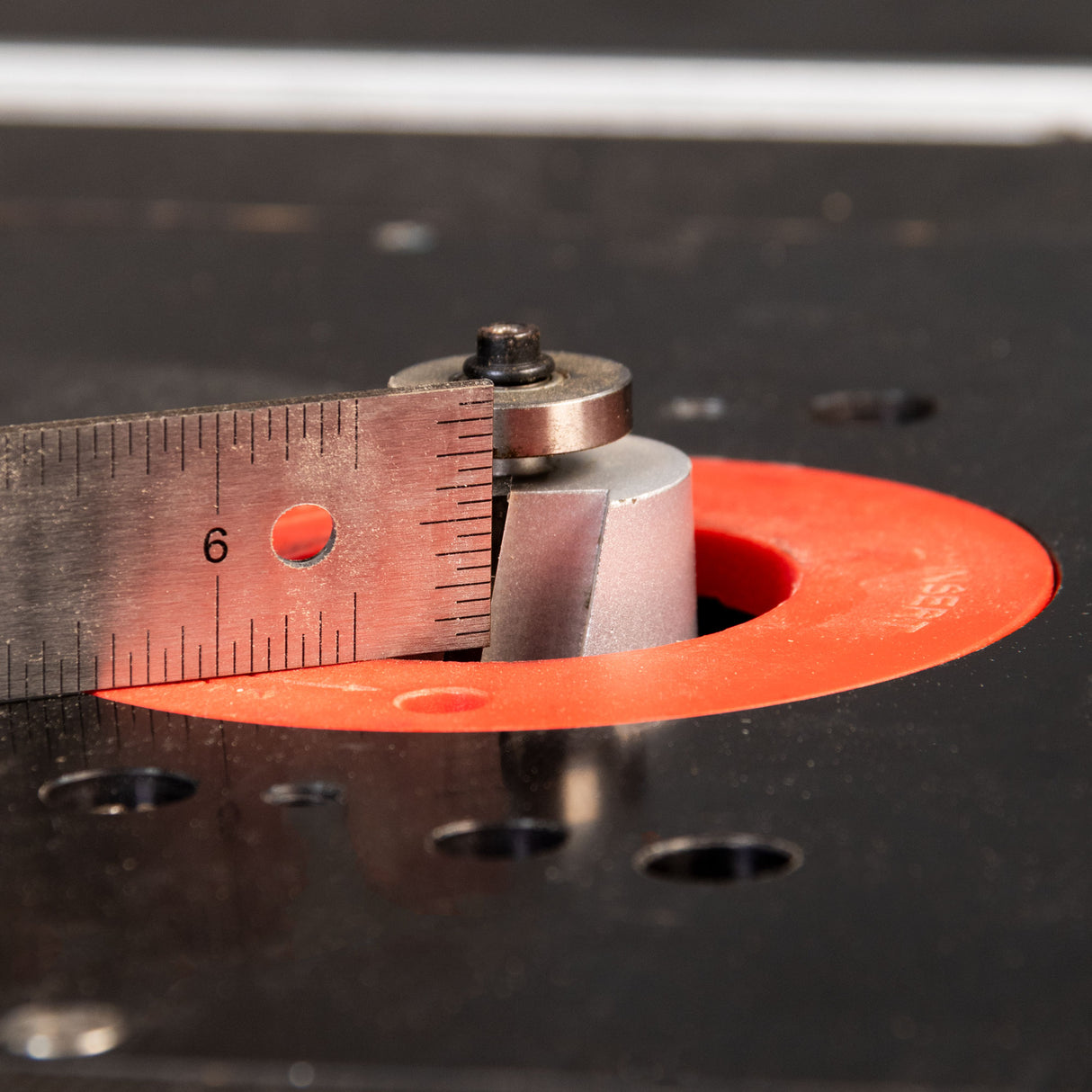 Close-up of a metal ruler against a red circular object on a dark surface