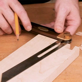 Woodworker using bevel gauge and pencil to mark angle on wooden board