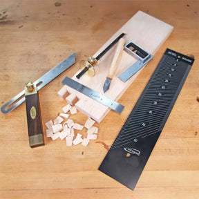 Woodworking hand tools including bevel gauge, square, marking gauge, chisel, and ruler on wood