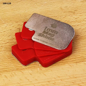 Stack of 1mm mag shims with red plastic and metal pieces on a wood surface