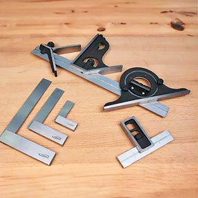 Assorted woodworking squares and measuring tools on a wooden workbench surface