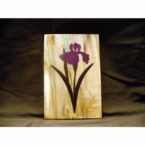 Wood inlay panel with purple iris flower design, woodworking project on natural wood background