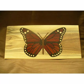 Wood inlay panel with red and black butterfly design on a natural wood background