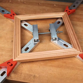 Woodworking picture frame clamped with metal corner clamp tool on workbench