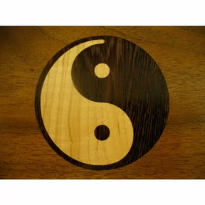 Wood inlay Yin Yang symbol with light and dark contrasting woods on a wood surface