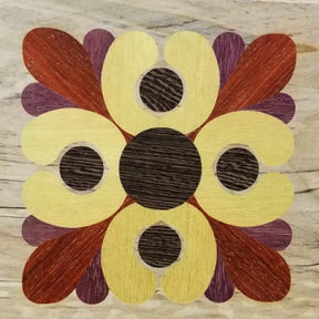 Geometric floral wood inlay design with yellow, brown, and reddish tones on light wood background