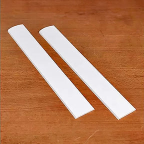 Pair of white jointer knives on wood surface for woodworking tool replacement