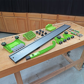 Woodworking featherboard and fence kit with green components laid out on a workbench
