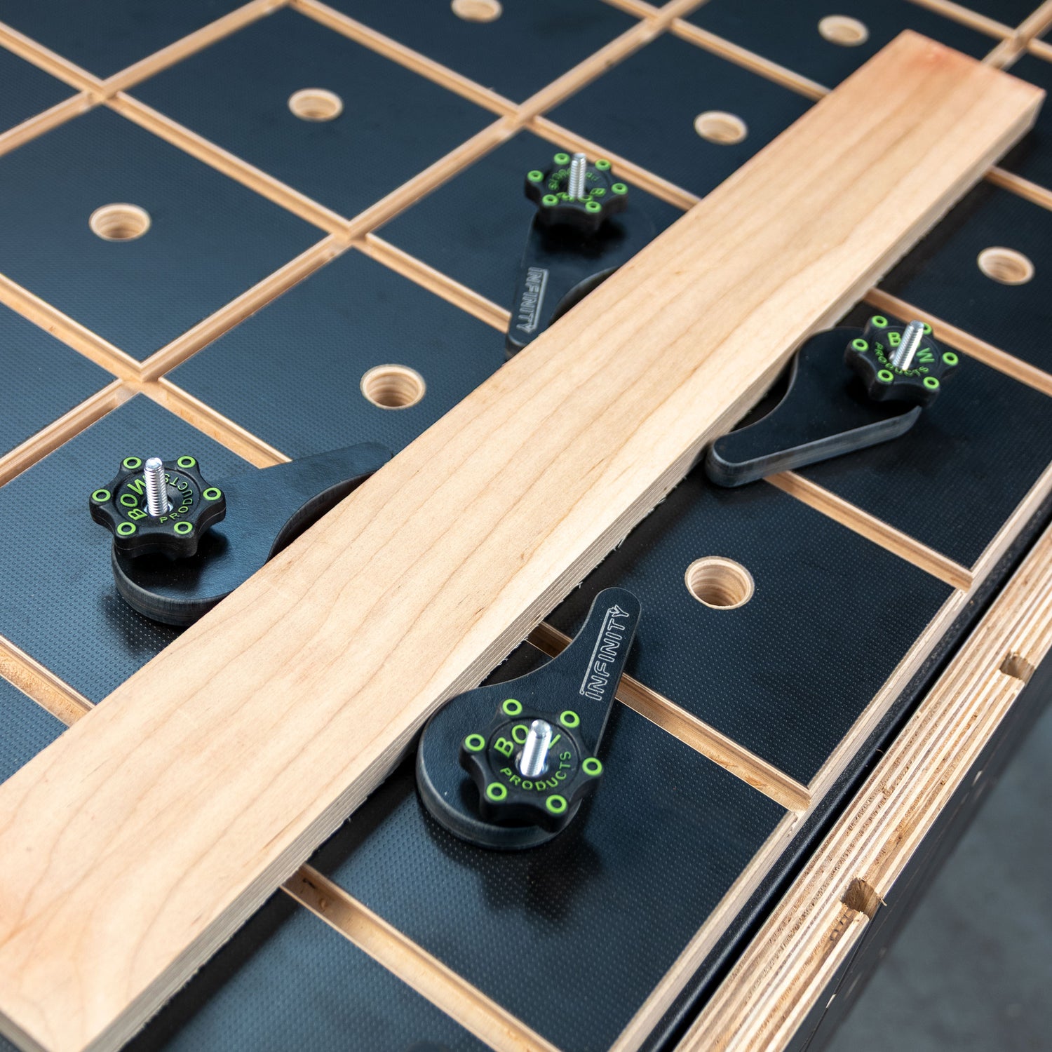 Eccentric cam clamps securing wood board on woodworking workbench with grid pattern