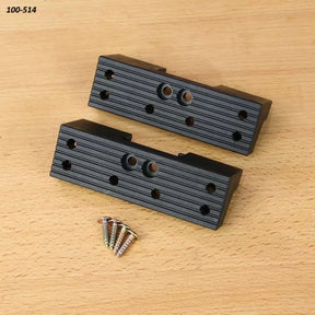 Set of two black plastic woodworking jig blocks with screws on wood surface