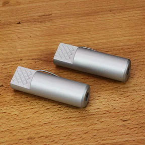 Pair of aluminum bench dogs for woodworking clamped on a wooden workbench surface.