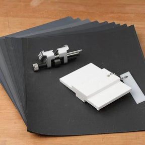Woodworking sharpening jig set with sanding sheets and alignment guide on wood surface
