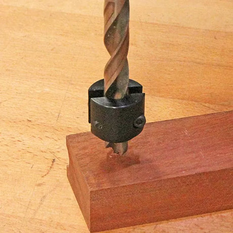 Drill bit with stop collar drilling into hardwood block on workbench, woodworking tool