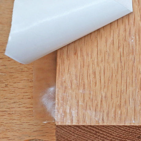 Peeling back adhesive tape from a wood board on a workbench, woodworking tool supply