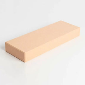 Beige rectangular sharpening stone for woodworking tools on a white background