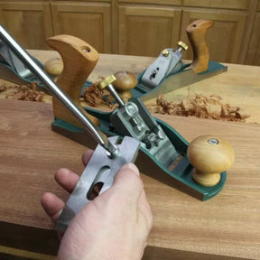 Hand adjusting woodworking hand plane tool on workbench with wood shavings