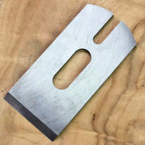 Steel woodworking plane blade on a wood background