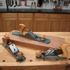 Set of three woodworking hand planes with wooden handles on a workbench in a workshop