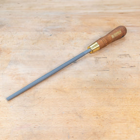 A round rasp sitting on a wooden bench.