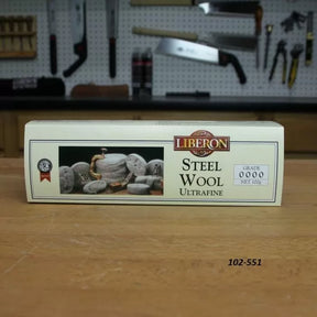 Liberon ultrafine steel wool grade 0000 box on woodworking bench, tools in background