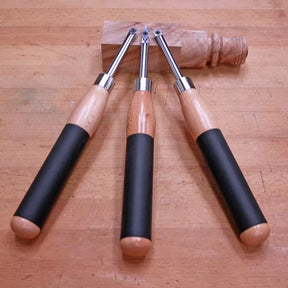 Woodturning carbide lathe tools with wooden handles on workbench beside turned wood piece