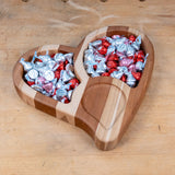 Heart-shaped wooden tray filled with red and silver wrapped chocolate candy on workbench