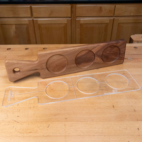 Clear acrylic cutting board template with three round cutouts on a wooden workbench