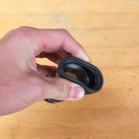 Hand holding flexible rubber dust collection fitting for woodworking tools on a workbench